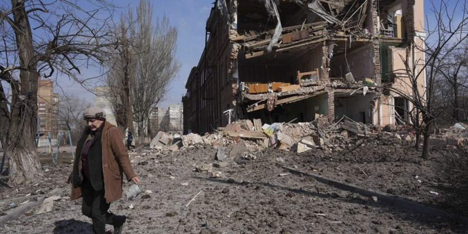 女子經過被砲擊的建築。馬里烏波爾，烏克蘭。