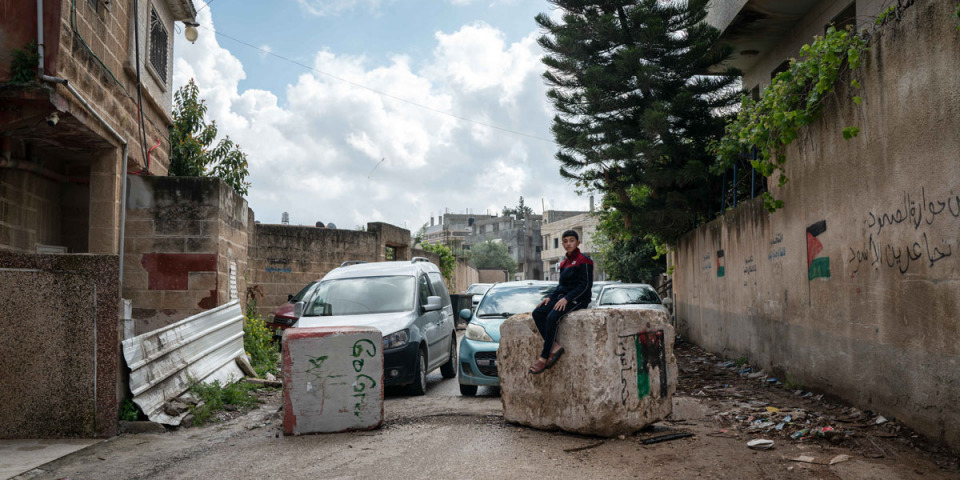 在自家門外，奧德（Hussam Odeh）坐在以色列士兵設置的路障上。© Samar Hazboun