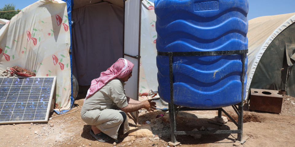 2023年5月，一名因土敘大地震而流離失所的男子，在敘利亞堅達里斯營地中使用一個無國界醫生安裝的水箱洗手。© Omar Haj Kadour / MSF