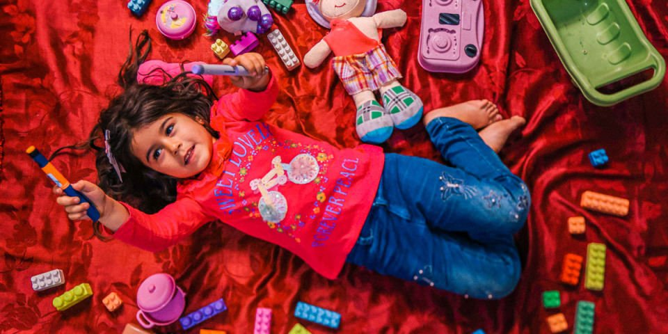 西瓦（Siwar）在臨時住所中躺在她的玩具裡，舉起她的胰島素筆。  西瓦和家人住在黎巴嫩北部的阿薩爾（Arsal），她從很小就被診斷出患有第一型糖尿病，必須經常前往鎮上的無國界醫生診所接受治療。