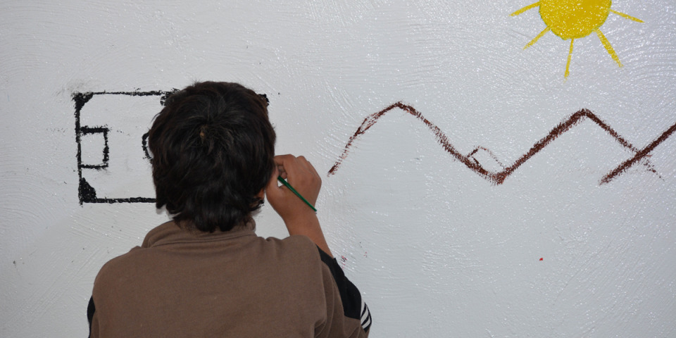 一名兒童在無國界醫生霍爾營地診所的牆上畫圖。攝2023年12月13日。©MSF
