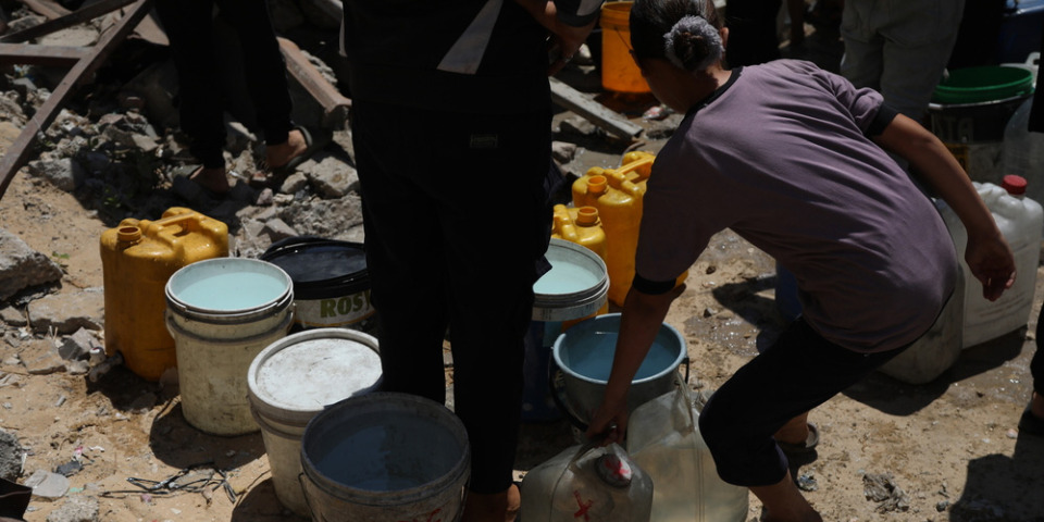 巴勒斯坦人拿著破舊的容器,等待卡車裝水。2025年8月。© MSF