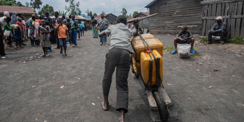 一名男子用當地的一種雙輪木車載送水桶。©MOSES SAWASAWA