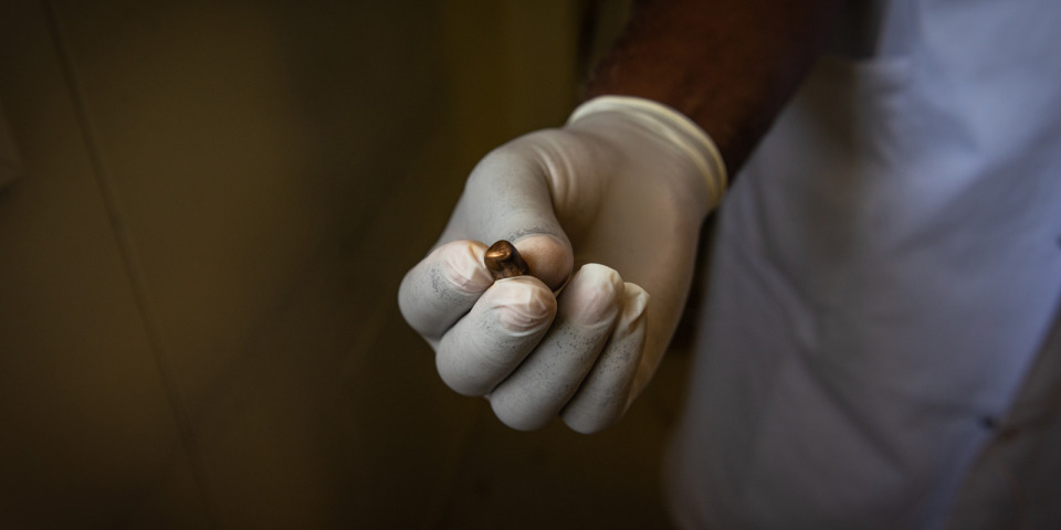 一名無國界醫生工作人員展示從一名受槍擊傷患身上取出的子彈。流彈，主要是大口徑子彈，正成為太子港日益嚴重的問題。攝於2022年6月。©Johnson Sabin