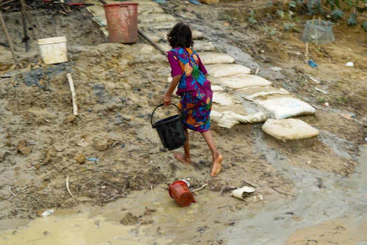 羅興亞女孩在傾盆大雨來臨前，提著水回帳篷。 ©Dalila Mahdawi/MSF