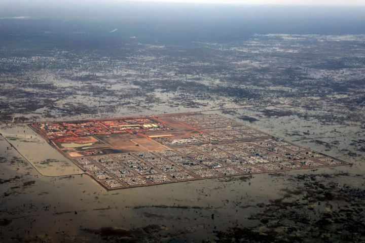 班提烏的流離失所者營地空拍照片，居住了12萬人的營地被洪水圍繞，土堤是營地僅有的防護。攝於南蘇丹，2022年4月。 © PETER CATON