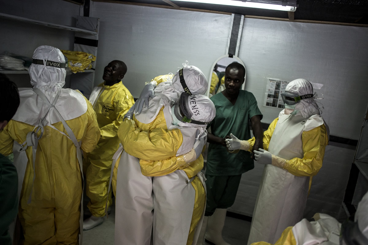 伊波拉治療中心裡，醫護人員於進入高危險區前穿起防護衣，並互相擁抱打氣。