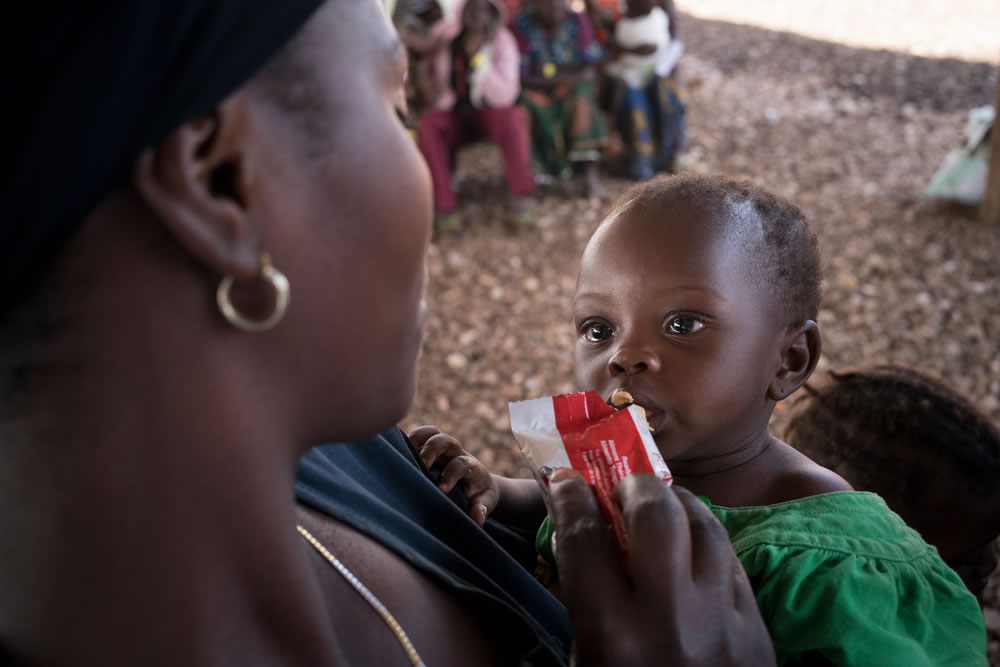 一位剛果難民媽媽正在用RUTF餵食小朋友。他們為了逃避戰火而來到烏干達。